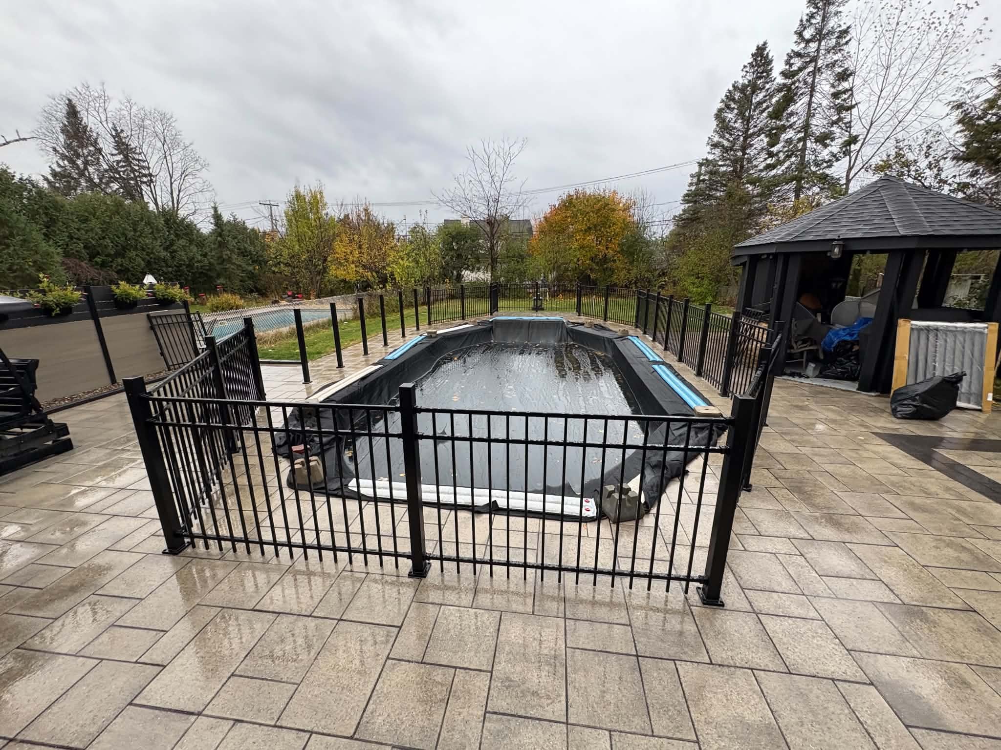 Cloture aluminium noire autour d'une piscine creusee avec gazebo